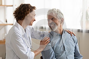 Cheerful healthy old male patient and caring doctor talking, bonding