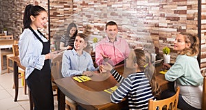 Cheerful hospitable waitress helping visitors