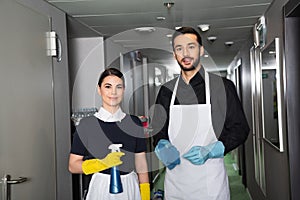 cheerful housekeepers in rubber gloves looking