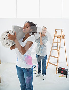 Cheerful housemates carrying rolled up rug