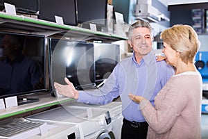 Cheerful husband and wife choose for themselves TV in center of electronics photo