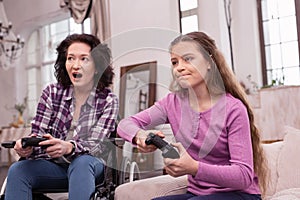 Cheerful incapacitated woman and girl competing in video game