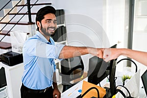 Cheerful Indian businessman partners making fist bump with a smile as a symbol of teamwork. Positive multi-ethnic business