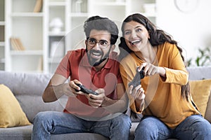 Cheerful Indian Couple Having Fun At Home, Playing Video Games Together