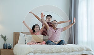 Cheerful indian family teenage boy son and girl with dad have fun and raising hands up together while relaxing and using laptop