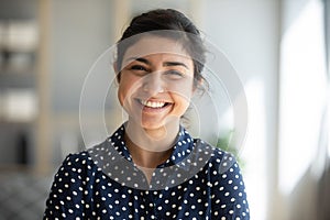 Cheerful indian girl standing at home office looking at camera photo