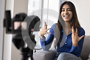 Cheerful Indian online influencer girl speaking at slr reflex camera