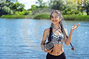 Cheerful Indian yogi woman with fitness mat against the river