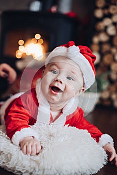 Cheerful infant in Santa clothes smiling at the camera