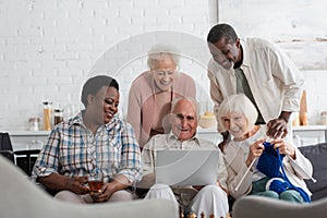 Cheerful interracial pensioners with yarn and