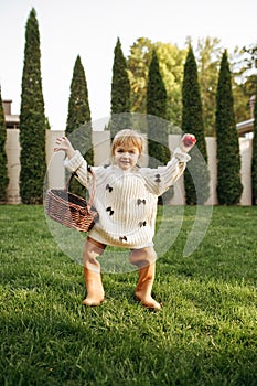 Cheerful kid with basket play in the garden