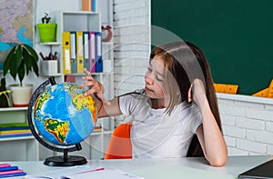 cheerful kid girl with globe at school lesson, geography