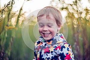 Cheerful kid toddler laughing outdoors. Child portrait in nature. Caucasian White boy.