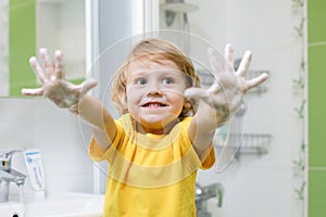 Kid washing hands and showing soapy palms photo
