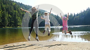 Cheerful kids jumping and enjoying during the summer vacation on a forest lake