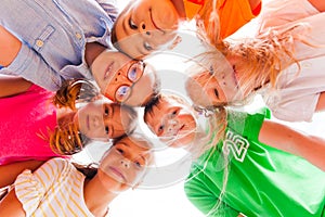 Cheerful kids standing closely in a circle touching their heads