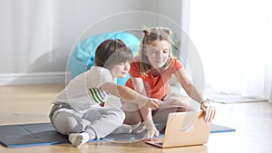 Cheerful kids waving goodbye and closing laptop. Portrait of positive Caucasian friends or brother and sister using