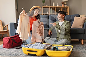 Cheerful Korean Travelers Spouses Packing Travel Suitcase Choosing Clothes Indoors