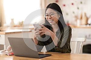 Cheerful korean woman entrepreneur working from home, using gadgets