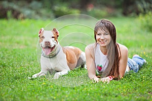 Cheerful lady lying on grass with dog.