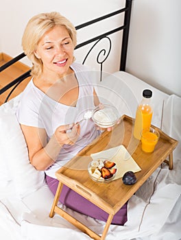 Cheerful lady with orange juice, berries and yogurt