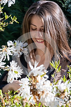 Cheerful lady smiles looking at beautiful white blossoms