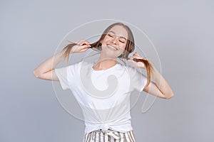 Cheerful lady in striped pants fooling around in studio and holding her hair