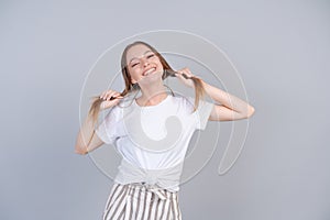 Cheerful lady in striped pants fooling around in studio and holding her hair