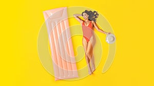 Cheerful Lady In Swimwear Lying Near Inflatable Lilo, Yellow Background