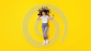 Cheerful Lady Using Phone Listening Music Wearing Headphones, Yellow Background