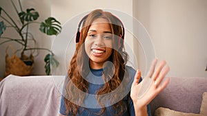 Cheerful Latin woman with headphones talks on videocall photo