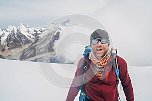 Cheerful laughing climber in sunglasses portrait with backpack ascending Mera peak high slopes at 6000m enjoying legendary Mount