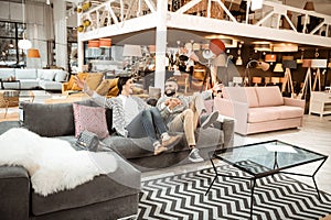 Cheerful laughing couple behaving childishly in furniture showroom photo
