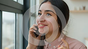 Cheerful laughing Indian Arabian girl gen z student speak mobile phone at office casual carefree conversation happy