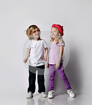 Cheerful laughing kids girl and boy in t-shirts and jeans stand close together, dancing