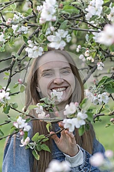 Cheerful laughing young woman near an apple blossom. Girl with natural beauty in spring apple orchard