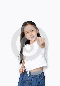 Cheerful little Asian girl child pointing at you and looking camera isolated over white background. Kid point to front