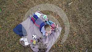 cheerful little baby boy plays with cones and other toys on carpet in the wood.