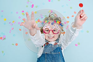 Cheerful little birthday girl lies on a floor, her hands extended up