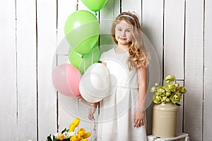 Cheerful little blonde girl with balloons on white wood background