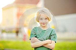 Cheerful little boy enjoying warm sunny summer day of holidays. Active child playing on the street of small town. Freedom, rest,