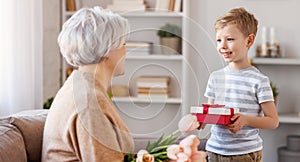 Cheerful little boy giving present to grandmother