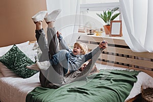 Cheerful little boy having fun with mother on sofa