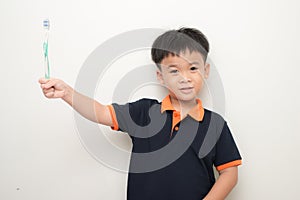 Cheerful little boy holding a tooth brush over white background, Studio portrait of a healthy mixed race boy with a toothbrush is
