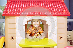 Cheerful little boy playing in a playhouse