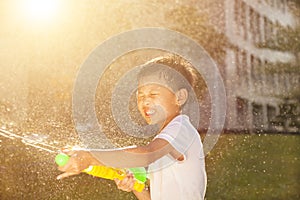 Cheerful little boy playing water guns in the park