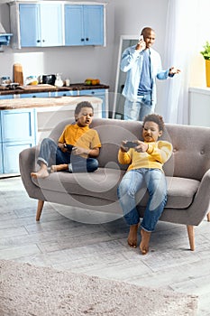 Cheerful little boys sitting on sofa and playing video games