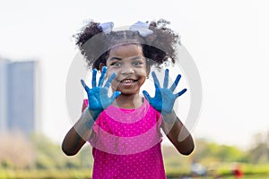 Cheerful little child girl showing painted hand, Cute little kid girl playing outdoors in the garden