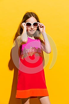 Cheerful little fashion girl posing with sunglasses