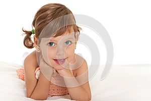 Cheerful little girl on the bedspread